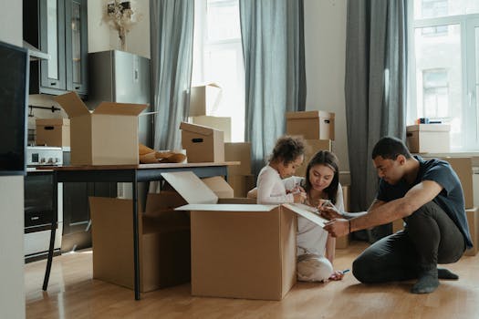 A person lying under a pile of moving boxes in a minimalistic room conveys tiredness from packing, a common experience when moving into Rent to Own Residences for Canadians Nationwide.