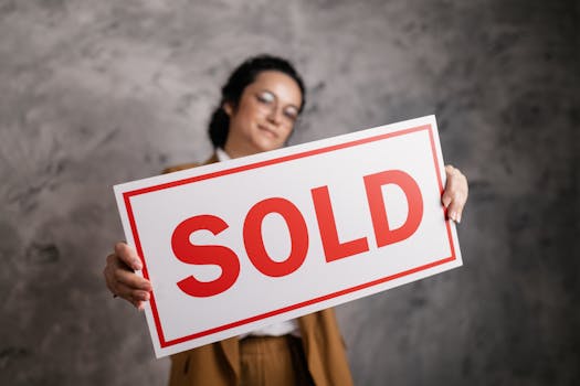 A smiling woman with eyeglasses holding a 'Sold' sign, signifying success in real estate sales in Canadian Homes with Rental-to-Ownership Pathways.