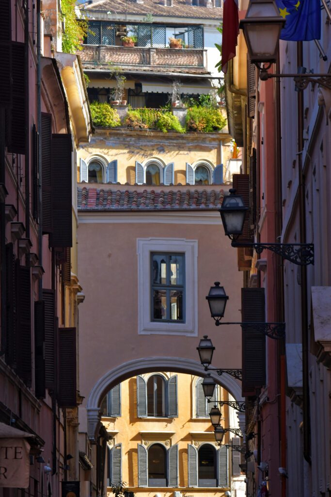 Picturesque alleyway with historic architecture and vibrant greenery in a European city.
