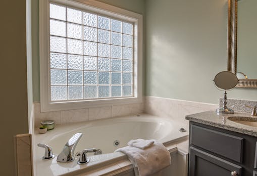 Stylish modern bathroom featuring a luxury bathtub, sleek sink, and large window. Perfect for relaxation.