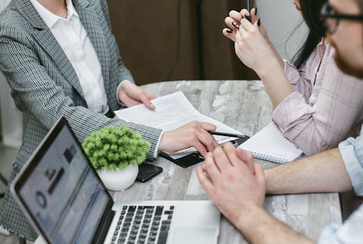 Three individuals collaborating on financial documents during a business meeting.