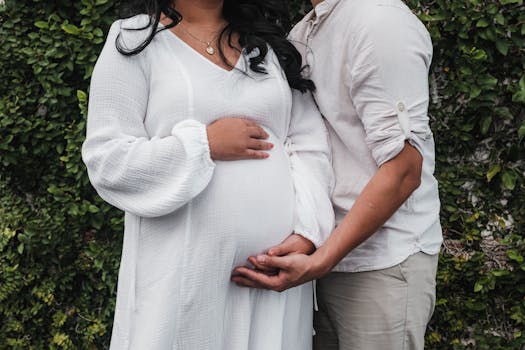 expecting couple poses in lush outdoor setting.