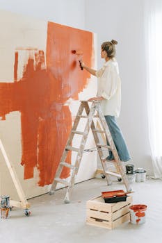 Mother and son smiling while painting a wall together in a home renovation project.