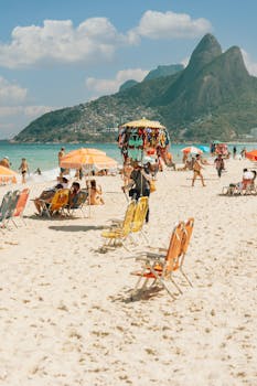 Sunny day at Ipanema Beach, Rio, with vibrant umbrellas and picturesque mountains.